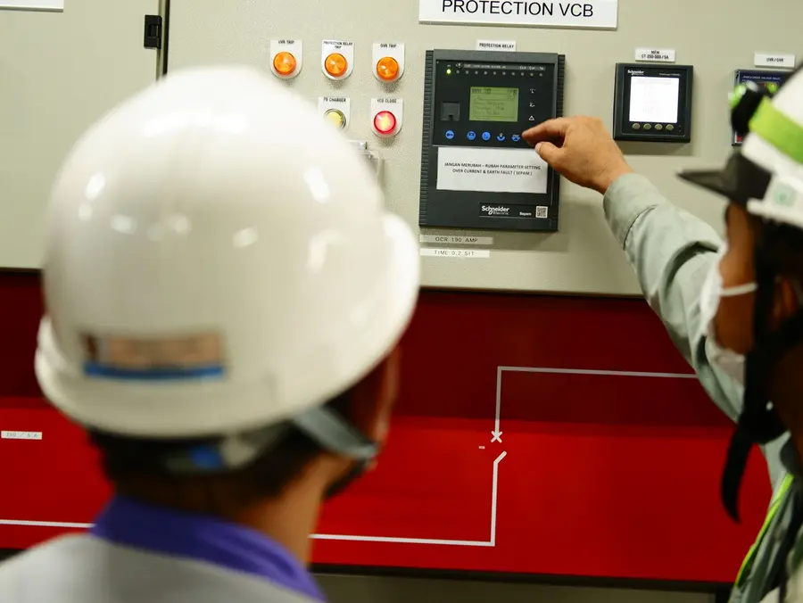 Technicians operating an industrial electrical panel