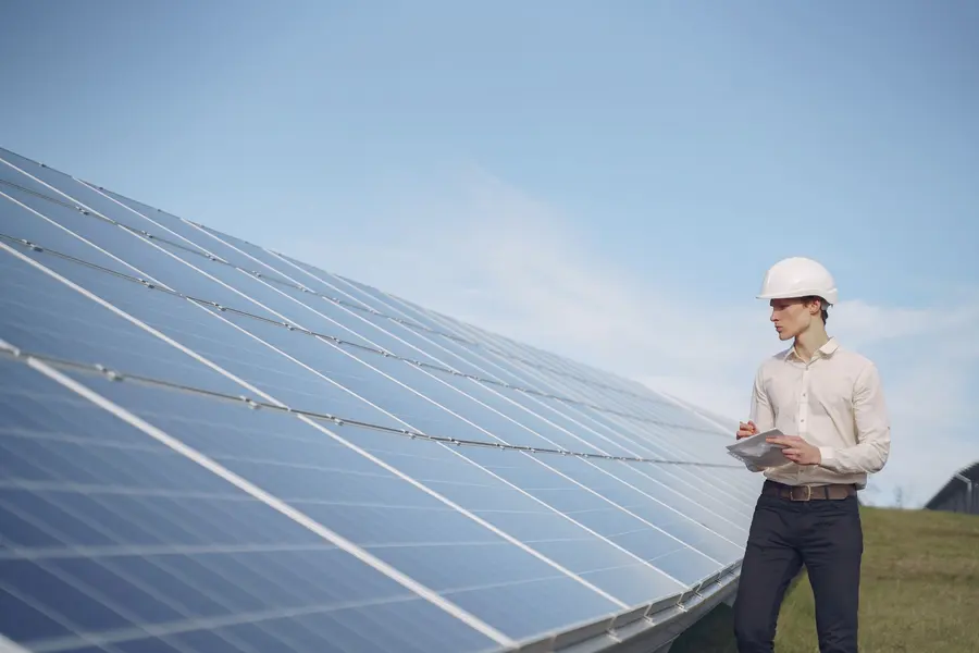 Ingeniero con casco y portátil entre paneles solares